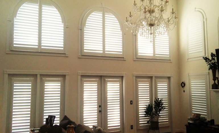 Entertainment room in two-story Washington DC house with plantation shutters on high windows.